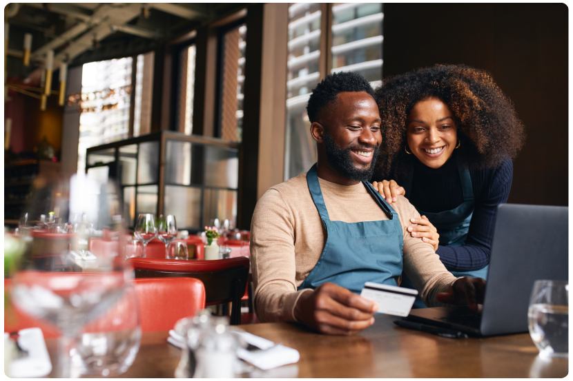 casal em mesa de restaurante analisando um notebook