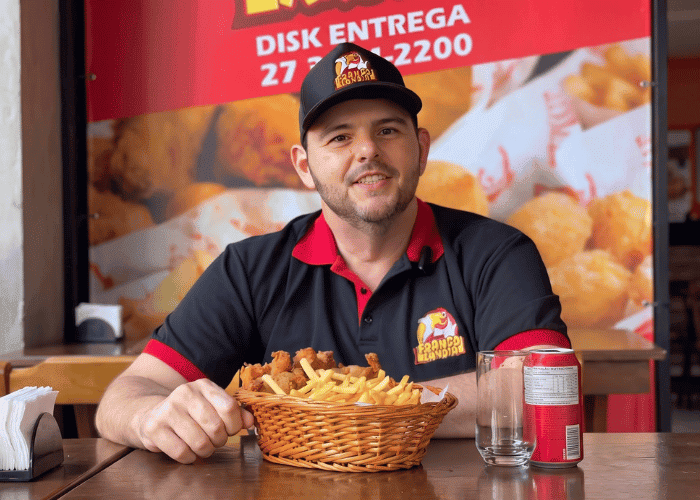 João proprietário da Frangolandia em frente a sua loja apresentando seu prato 