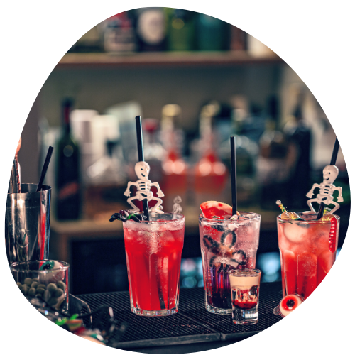 copos com bebidas avermelhadas e canudos com decorações de esqueletos 